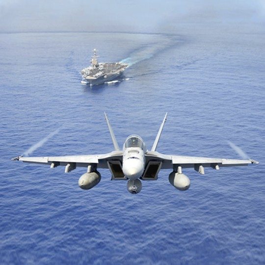 Aircraft carrier on the ocean and a fighter aircraft flying above