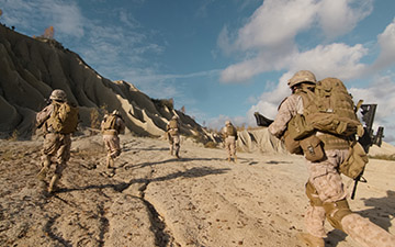 Warfighters running up a dirt hill